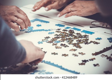 Family Hands Solving Jigsaw Puzzle At Home