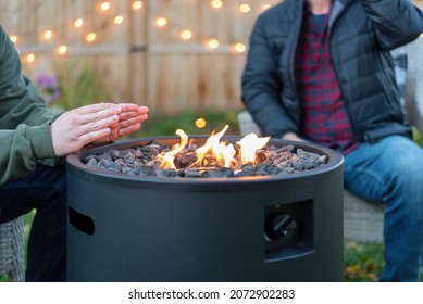 Family Hanging Out Around A Backyard Fire In Autumn