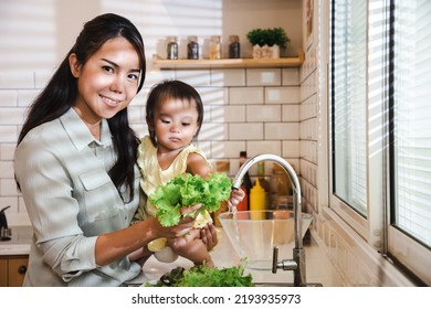 Family Happy Asian Mother And Daughter Washing Organic Vegetables Together In Kitchen At Home. Making Salad For Breakfast In Sunny Morning. Soft Focus