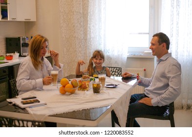 Family have breakfast at the table and drink orange juice in the morning. - Shutterstock ID 1220083552