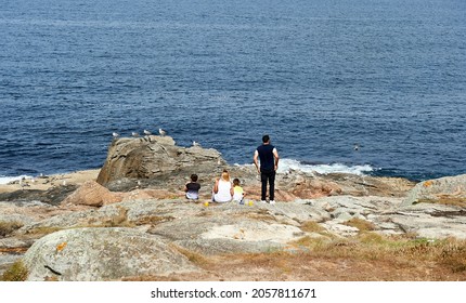 A Family Have A Picnic Overlooking The Sea While The Seagulls Are Perched On The Rocks