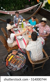 Family Having A Barbecue Party In Their Garden In Summer