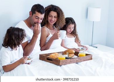 Family Having Breakfast In Bed At Home
