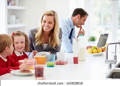 Family Having Breakfast In Kitchen Before School And Work