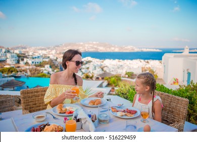 Family Having Breakfast At Outdoor Cafe With Amazing View. Adorable Girl And Mother Eating Croissant On Luxury Hotel Terrace