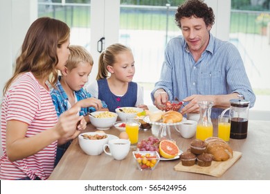 Family Having Breakfast At Table In House