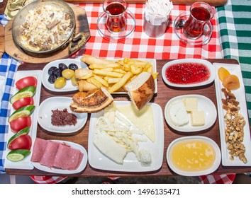 Family Having Delicious Rich Traditional Turkish Breakfast Include Tomatoes, Cucumbers, Cheese, Butter, Eggs, Honey, Bread, Olives, Jam, Sausage, Fried Potatoes And Tea Cups. 