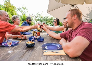 Family Having Fun Cheering With Wine At Barbecue - Multi Generational People Sitting In The Garden - Family And Summer Vacation Concept