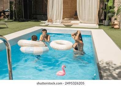 family having fun and enjoying swimming in backyard pool during summer holiday.