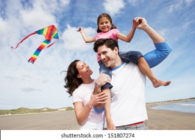 Family Having Fun Flying Kite On Beach Holiday