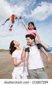 Family Having Fun Flying Kite On Beach Holiday