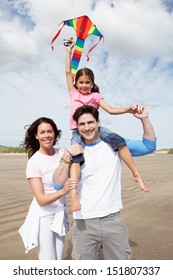 Family Having Fun Flying Kite On Beach Holiday