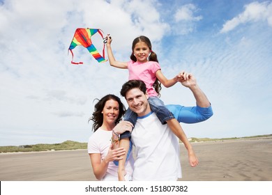 Family Having Fun Flying Kite On Beach Holiday