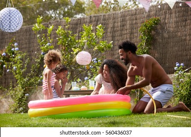 Family Having Fun In Garden Paddling Pool