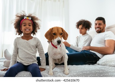 Family having fun with his pet in a bed. - Powered by Shutterstock