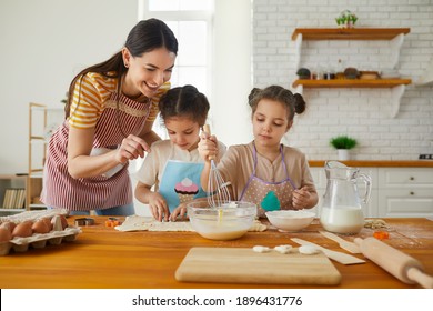 Family Having Fun Making Cakes And Cookies Together. Two Little Twin Sisters Cook Cookies In The Kitchen With Their Mother, Who Helps Them. Concept Of Homemade Food And Little Helpers.