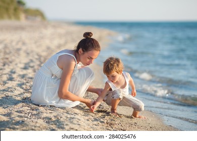 Family Having Fun On The Beach Collecting Seashells