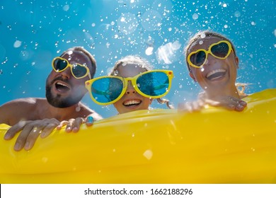 Family Having Fun On Summer Vacation. People Jumping In Swimming Pool. Active Lifestyle Concept. Spring Break!