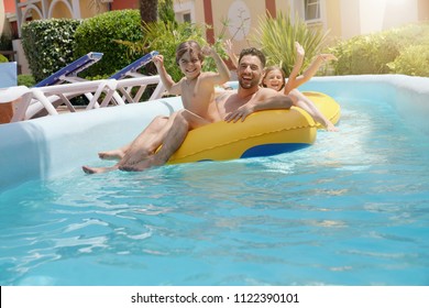 Family having fun riding inflatable ring at the pool