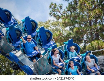 Family Having Fun Riding A Rollercoaster At A Theme Park. Screaming, Laughing And Enjoying A Fun Summer Vacation Together.