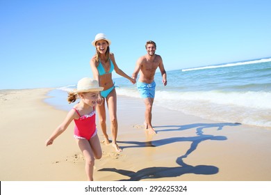 Family Having Fun Running On A Sandy Beach