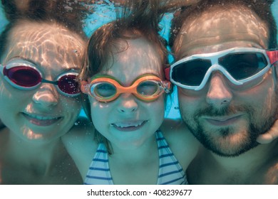 Family Having Fun In Swimming Pool. Underwater Funny Portrait. Summer Vacation