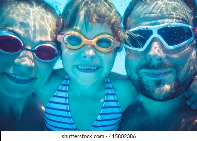 Family Having Fun In Swimming Pool. Underwater Funny Portrait. Summer Vacation