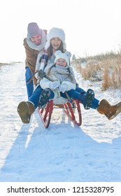 Family Having Fun With Toboggan In Winter In The Snow