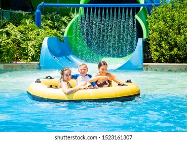 Family having fun together a water park. Riding on an inflatable tube together on a water slide.