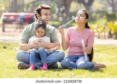Family having fun while blowing bubbles with daughter at park - Shutterstock ID 2126828738