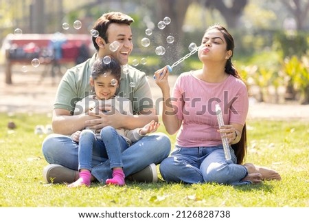 Family having fun while blowing bubbles with daughter at park