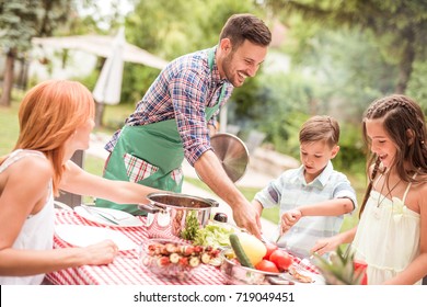 Family Having A Lunch In Their Garden In Summer.