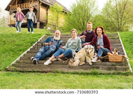 family having picnic while kids having fun near by in village