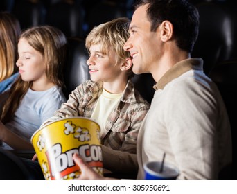 Family Having Popcorn While Watching Movie In Cinema Theater