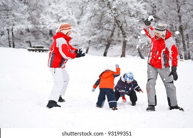 Family Having Snowball Fight In Snowy Woodland