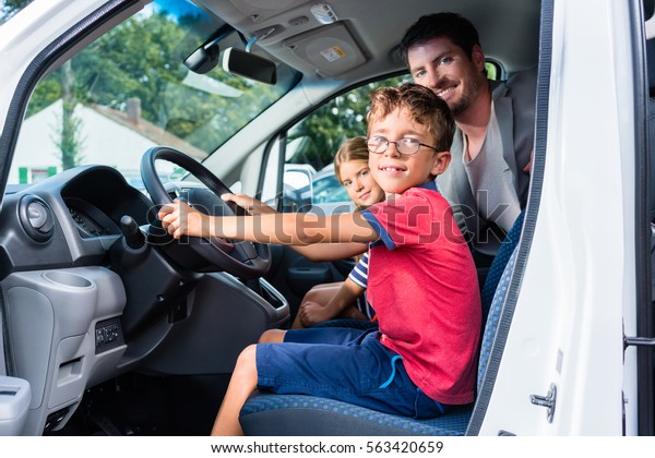 Family having test drive of new car at\
dealership, young son on the steering\
wheel