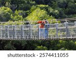 family hike with backpacks. mother and son walk along the suspension bridge. trekking in the mountains.