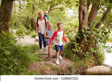 Family Hiking Along Path By River In UK Lake District