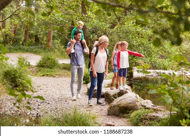 Family Hiking Along Path By River In UK Lake District