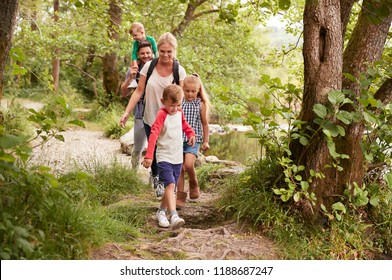 Family Hiking Along Path By River In UK Lake District