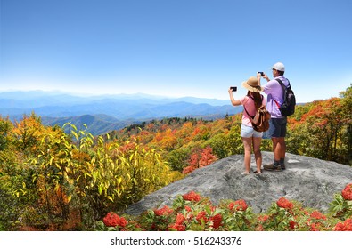 Family Hiking In Autumn Mountains Enjoying Beautiful Mountain View. Father And Daughter On Top Of Mountain, Taking Photos Of Beautiful Mountains With Iphones. North Carolina, USA.