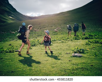 Family Hiking In The Mountains. A Young Happy Mother And Her Son Take A Hike Together In The Mountains On A Beautiful Summer Evening. Smile And Enjoying Their Time Together