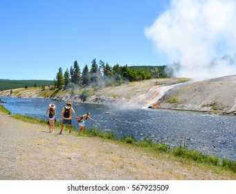 Family Hiking On Summer Vacation. Father Holding Child's Hand. The Water From The Springs Flowing Into The Firehole River, Yellowstone National Park. Wyoming, USA.