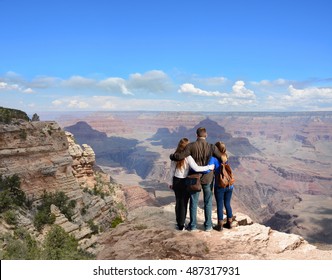 Family Hiking On Vacation, Standing With Arms Around On Top Of The Mountain, Looking At Beautiful Summer Mountains Landscape. Blue Sky In The Background. Grand Canyon National Park, Arizona, USA.