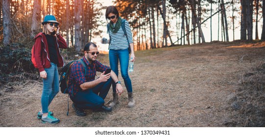 Family Hiking In The Pine Forest And Using Smart Phone To Navigate