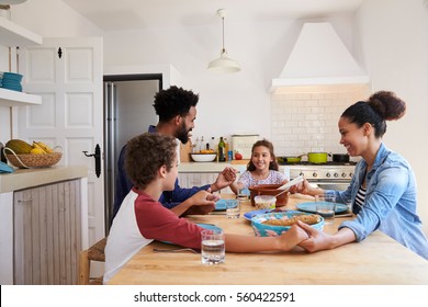 Family hold hands around the kitchen table before their meal