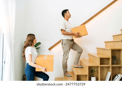 family holding box moving up stairs in new home. wife and husband help lifting packaging box to next floor relocating preparing new house. lover together carrying cardboard box up next level of house. - Powered by Shutterstock