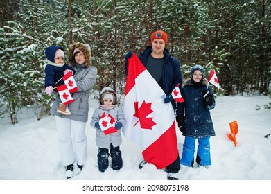 Family Holding Flag Of Canada On Winter Landscape.