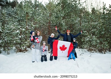 Family Holding Flag Of Canada On Winter Landscape.