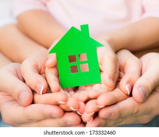 Family Holding Green Paper House In Hands. Real Estate Concept